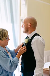Wedding party member fastening the groom’s boutonniere before the ceremony