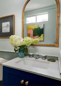 Artful bathroom design with hydrangeas vase, bamboo edge mirror, and wall art, by Jennifer Smith Design.