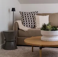 Living room nook styling with a brown couch, patterned pillows, side table, and floor lamp.