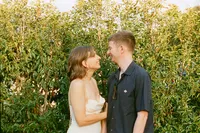 Couple laughing together by a hedge at Kites Barn, 35mm film wedding photograph