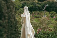 Bride from behind in a garden with a classical statue, Keith Marrison Oxfordshire wedding photographer