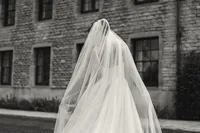 Playful shot of the bride's veil billowing over her face outside a historic stone building