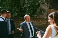 Bride and groom greeting a smiling guest on an Oxford street after the ceremony, 35mm film wedding photograph