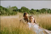 Couple sitting in long golden grass at Shotover Country Park, Oxford, 35mm film engagement photograph