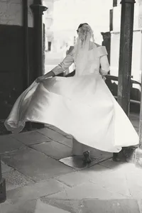 Bride twirling her wedding dress in a stone archway doorway, black and white photo, Worcester College Oxford