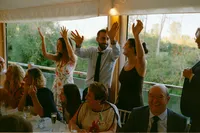 Wedding guests cheering with arms raised during the speeches, Oxford, 35mm film