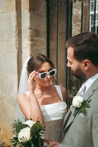 Bride wearing sunglasses smiling at groom in a playful moment