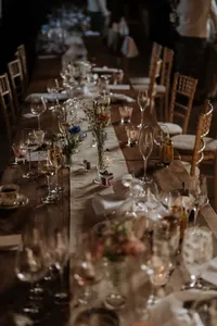 Rustic wedding reception table set with glassware, candles and floral arrangements