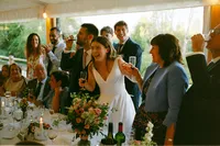Bride laughing with guests at the wedding breakfast in a riverside marquee, Oxford, 35mm film