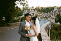 Couple embracing on the bridge in Castle Combe village, 35mm film wedding photograph