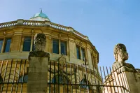 Stone heads outside the Sheldonian Theatre in Oxford against a blue sky, 35mm film wedding photograph