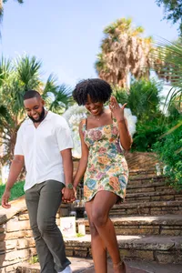 Engaged couple holding hands outdoors as she shows her engagement ring
