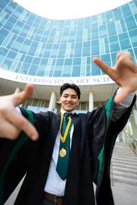 University of South Florida graduate reaching toward the camera outside a campus building