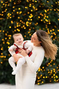Mother smiling at her baby in front of warm holiday lights