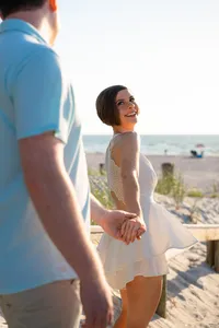 Couple holding hands on a Florida beach as she looks back smiling