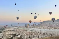 Hot air balloons floating above Cappadocia's dramatic rock formations at sunrise