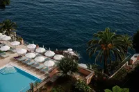 Luxury coastal resort overlooking turquoise Mediterranean waters with boats and palm trees