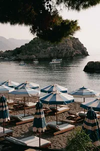 Lakeside waterfront with blue umbrellas, boats, and mountain views