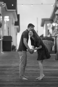 Black and white engagement portrait of a couple laughing together at Broadway at the Beach in Myrtle Beach, South Carolina, photographed by Amberlee Christey.
