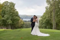 Bride and groom embracing on a scenic golf course overlooking a lake and West Virginia mountains, photographed by Amberlee Christey.