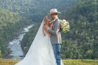 Bride and groom overlooking a scenic river and mountain valley during their Wilderness Lodge wedding in West Virginia, photographed by Amberlee Christey.