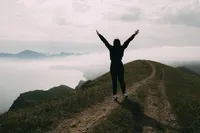 a-person-in-black-jacket-standing-on-green-mountain-8713093