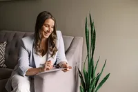 Amber Weingart, traditional naturopath, smiling while taking client notes at Opulent Natural Health in Bloomington, MN