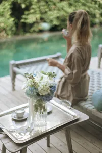 opulent-natural-health-table-with-vase-of-flowers-near-woman-by-pool