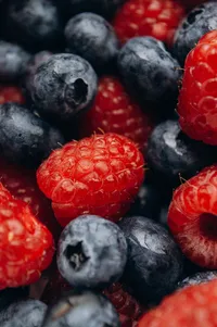 Fresh raspberries and blueberries piled together in a colorful close-up