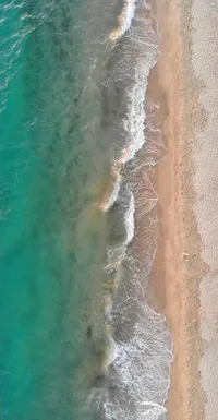 Aerial view of a peaceful shoreline with turquoise water and sandy beach, reflecting natural wellness and tranquility