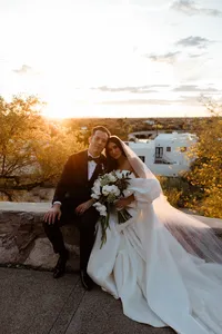 Bride and groom seated together with a white floral bouquet during golden hour overlooking the Arizona desert.