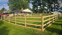 Three-rail wood farm and paddock fence with welded wire mesh installed across a residential yard in the Baltimore area by Blue Crab Fence & Home.