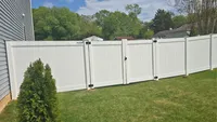 A solid white vinyl privacy fence featuring a wide, heavy-duty double drive gate with black metal hardware, securing a residential driveway in the Baltimore area.