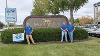 Blue Crab Fence & Home owners Jim, Brent, and Brian pose with their company yard sign in front of the Hunt Valley welcome sign.