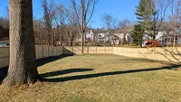 A custom 3-rail wood farm fence with wire mesh providing a secure, open-view boundary for a large residential backyard in Ellicott City.