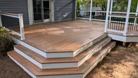 Multi-level Fiberon composite deck featuring warm brown boards, wrap-around steps, and crisp white fascia in Elkridge, MD, built by Blue Crab Fence & Home.