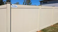 A solid tan vinyl privacy fence featuring a Blue Crab Fence & Home installation plaque, providing a secure boundary for a residential backyard in Odenton.
