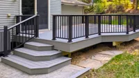 Custom composite deck stairs featuring crisp gray risers and black aluminum railing in the Baltimore region, built by Blue Crab Fence & Home.