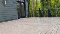 A spacious custom composite deck featuring sleek black aluminum railings, built onto a modern dark gray home in Davidsonville.