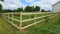 A heavy-duty 3-rail wood farm fence with wire mesh providing a secure boundary for a large, open Maryland property.