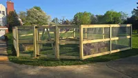 A 3-rail wood farm fence backed with wire mesh and a matching gate, securing a residential driveway in Catonsville.
