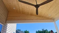 A detailed view of a custom covered deck featuring a natural wood plank ceiling, recessed lighting, and a modern ceiling fan in the Baltimore Metro area.