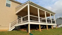 Elevated covered composite deck featuring a custom roof overhang, ceiling fans, and white railings in the Baltimore area, built by Blue Crab Fence & Home.