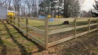 A heavy-duty 3-rail wood farm fence with wire mesh securing a large residential yard space in Maryland.