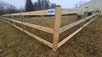 An angled corner section of a newly installed 3-rail wood farm fence enclosing a Maryland yard.