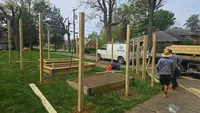 Blue Crab Fence team members setting heavy-duty wooden posts to build a custom enclosure around raised front yard garden beds in Maryland.