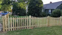 A traditional wood spaced picket fence enclosing the front yard of a residential property in the Baltimore area.