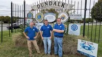 Blue Crab Fence & Home owners Jim, Brent, and Brian pose with their yard sign in front of the Dundalk Serving The Community sign.