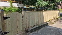 A classic wood privacy fence securing a residential property line along a paved driveway area in a Baltimore neighborhood.