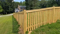 A custom wood privacy fence expertly stepped to accommodate the slope of a grassy residential yard in Maryland.